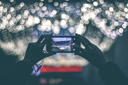 Frau fotografiert mit einem Handy in eine Lichtquelle